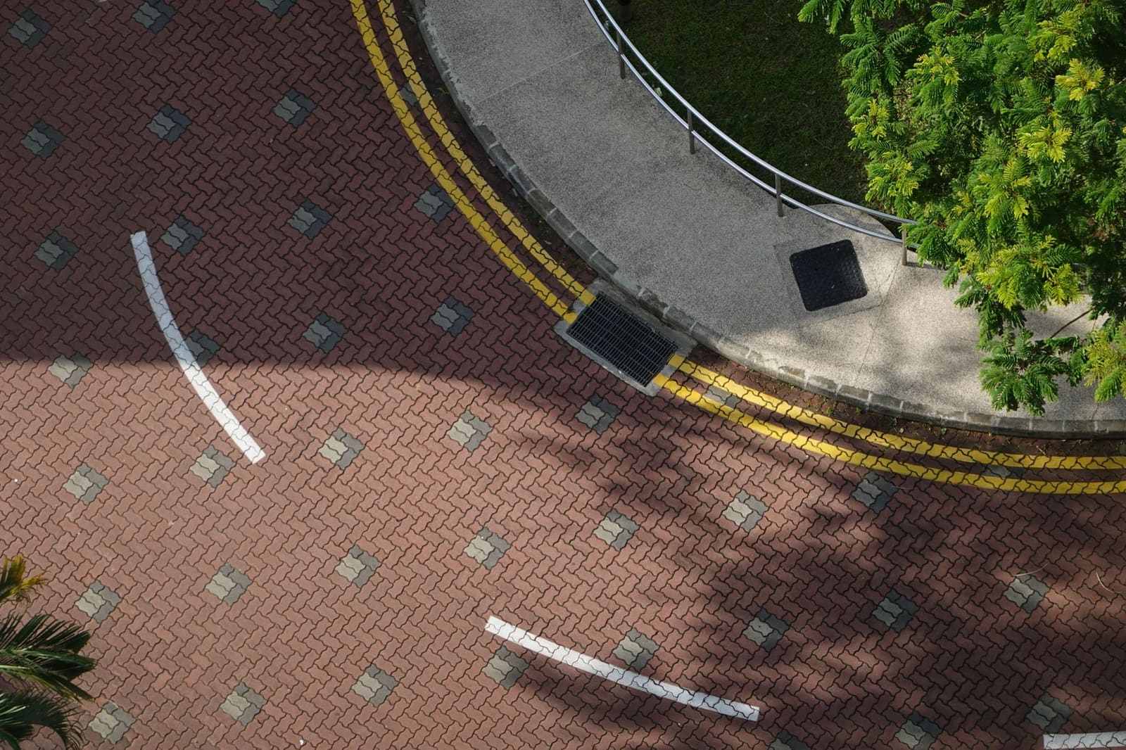 Bestrating van klinkers met een afvoerrooster en een trottoirband, van bovenaf gezien